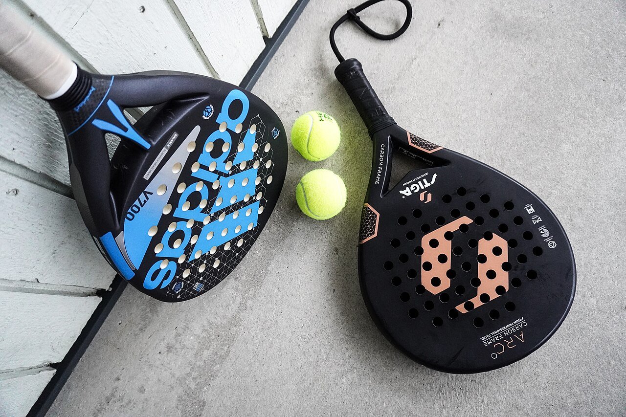 Raquettes de padel Adidas et Stiga avec deux balles, équipement caractéristique du sport