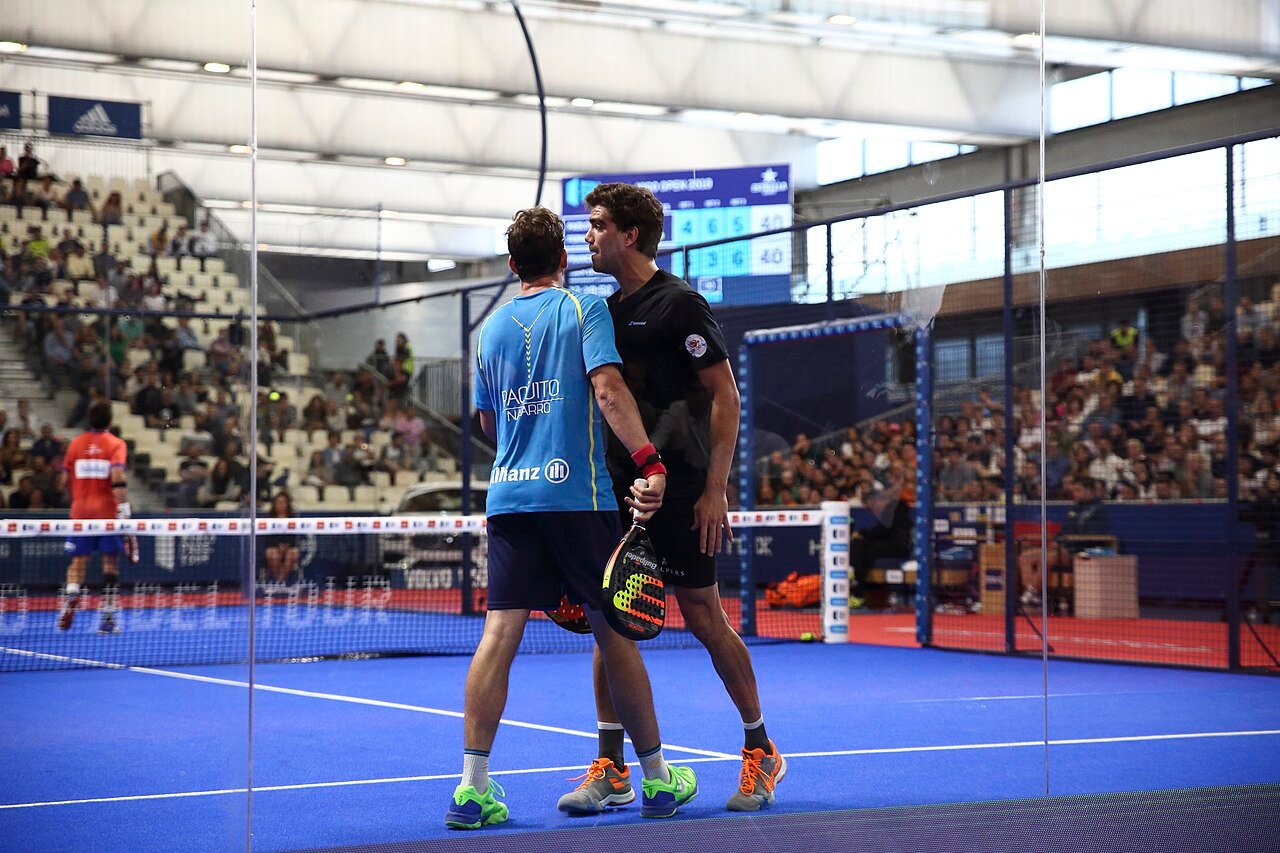 Deux joueurs de padel en double, vus de dos pendant un échange — illustration du jeu en équipe