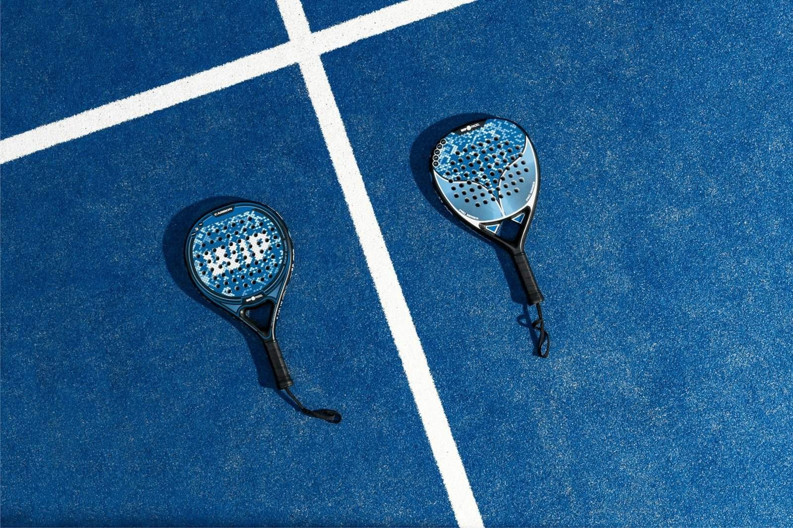 Deux raquettes de padel au noyau en mousse posees sur un court bleu