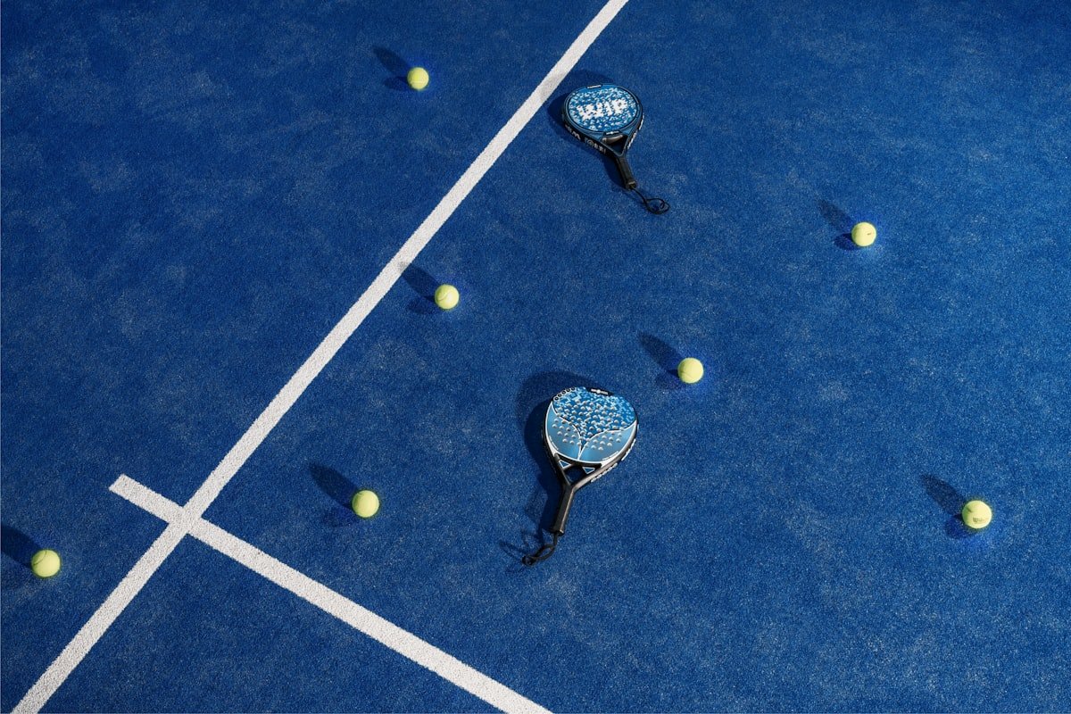 Deux raquettes de padel et balles sur un court bleu — padel outdoor indoor différences