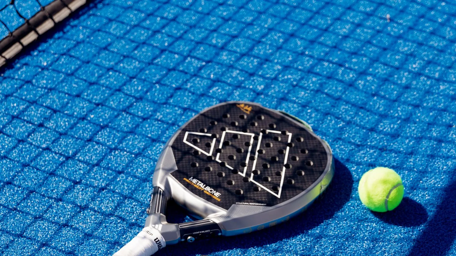 Raquette de padel et balle posées sur un court
