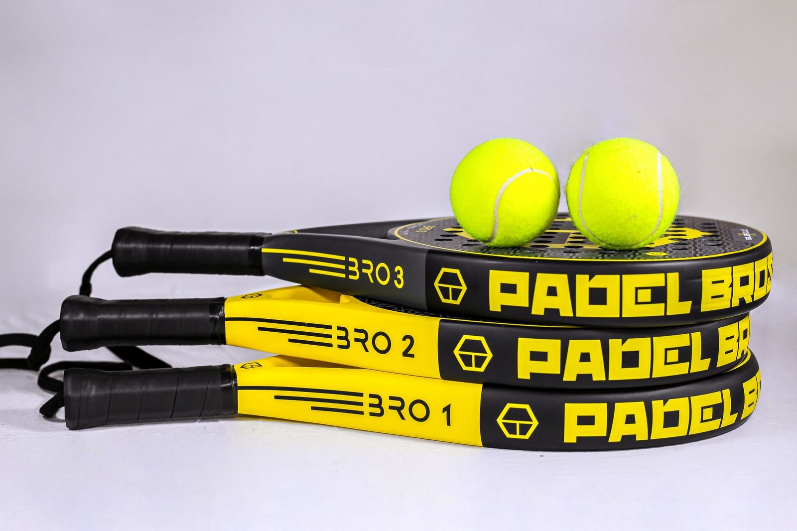 Trois raquettes de padel posées avec deux balles