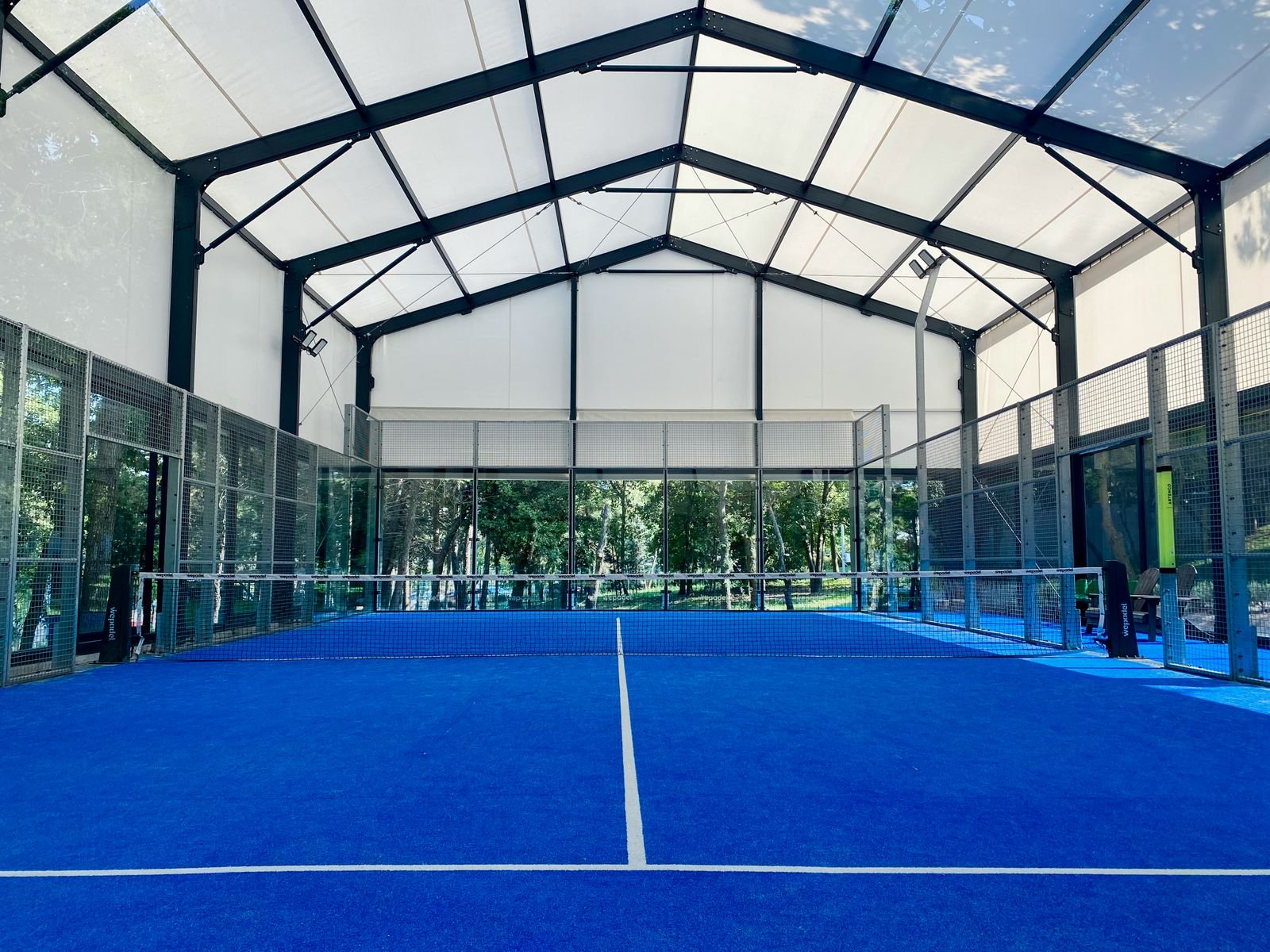 Court de padel intérieur au sol bleu, prêt pour une session