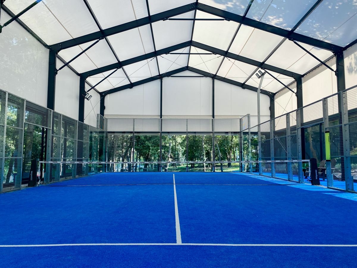 Court de padel bleu sous une structure couverte